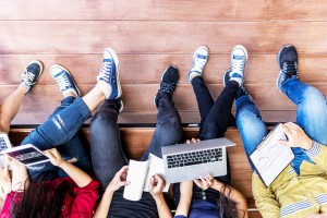 Schüler und Schülerinnen mit Laptop, Notizbuch und Tablet.
